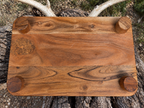 Underside of rustic hunting board showing four round riser legs and wood grain