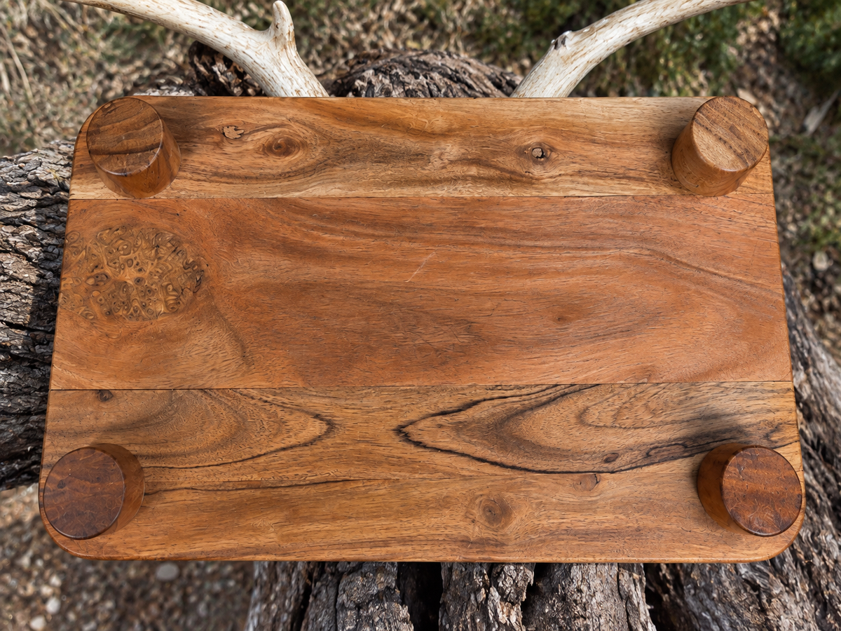 Underside of rustic hunting board showing four round riser legs and wood grain